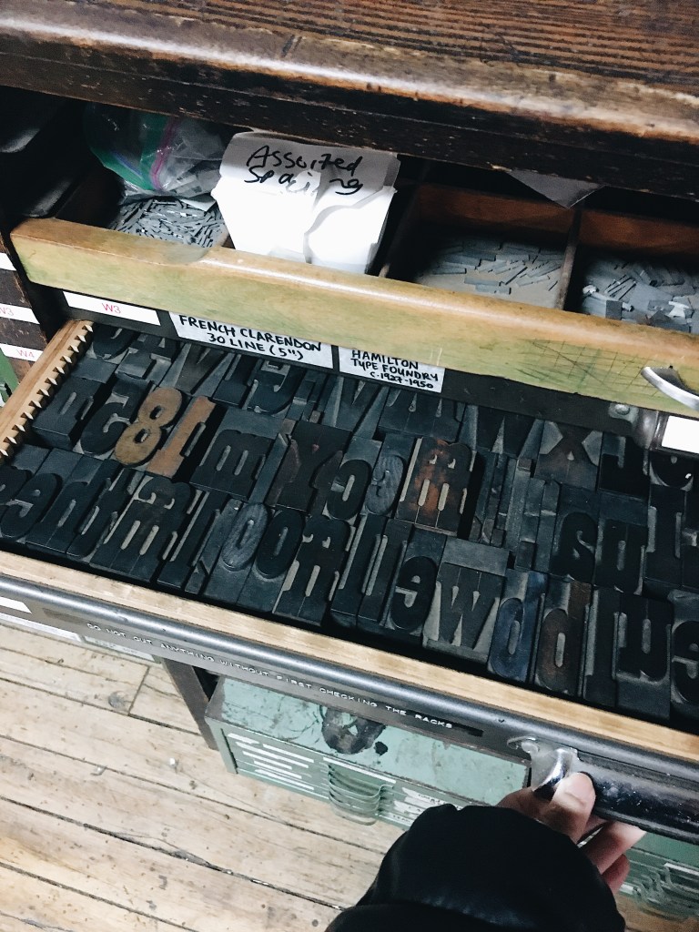 Yang Pulongbarit-Cuevo pulling out a drawer of uppercase woodblocks used for letterpress printmaking